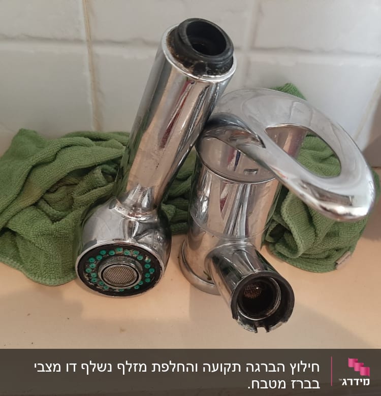 ברז מתכת מונח על מטלית ירוקה